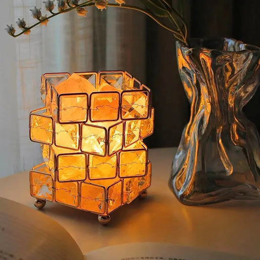 Decorative lamp with geometric design on a surface next to a clear vase.