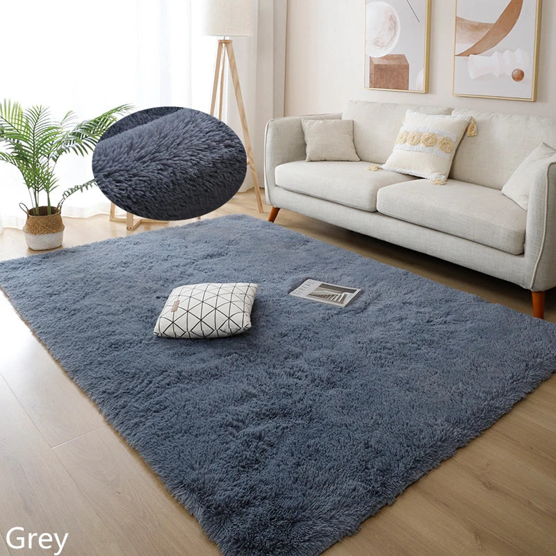 Living room with a large blue rug, white sofa, and decorative items.