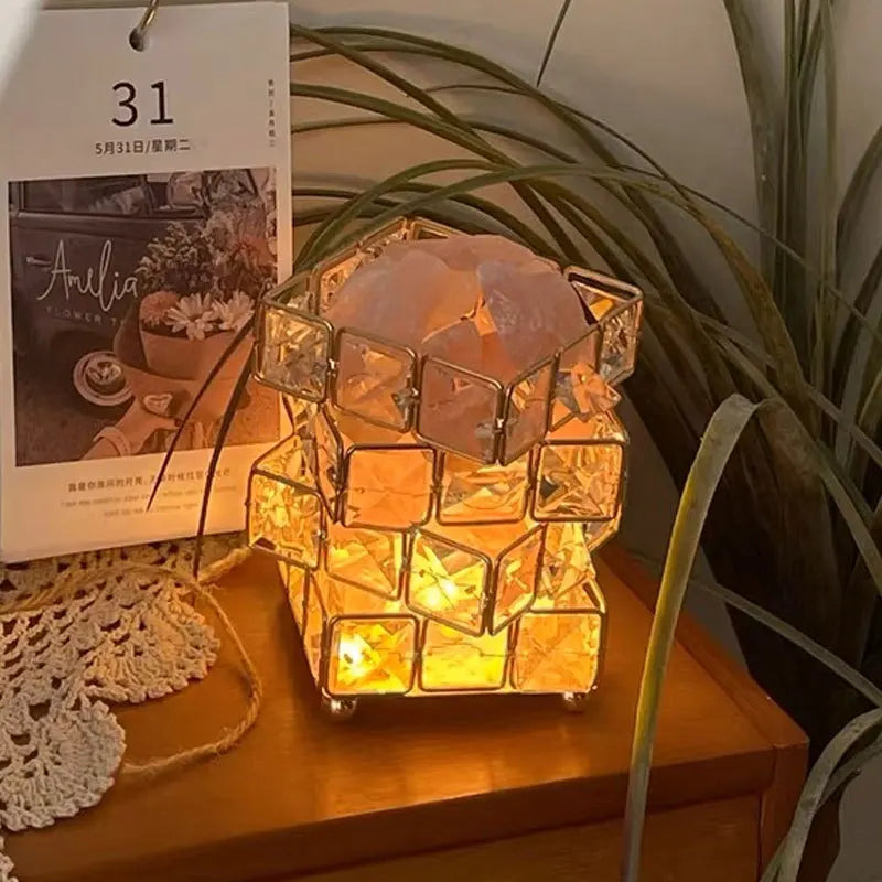 Decorative lamp with geometric design on a wooden surface next to a plant and calendar.