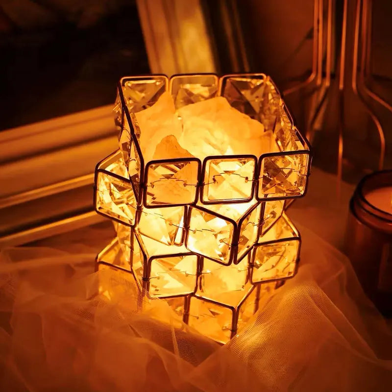 Decorative glass lantern with a warm glow on a soft fabric surface.