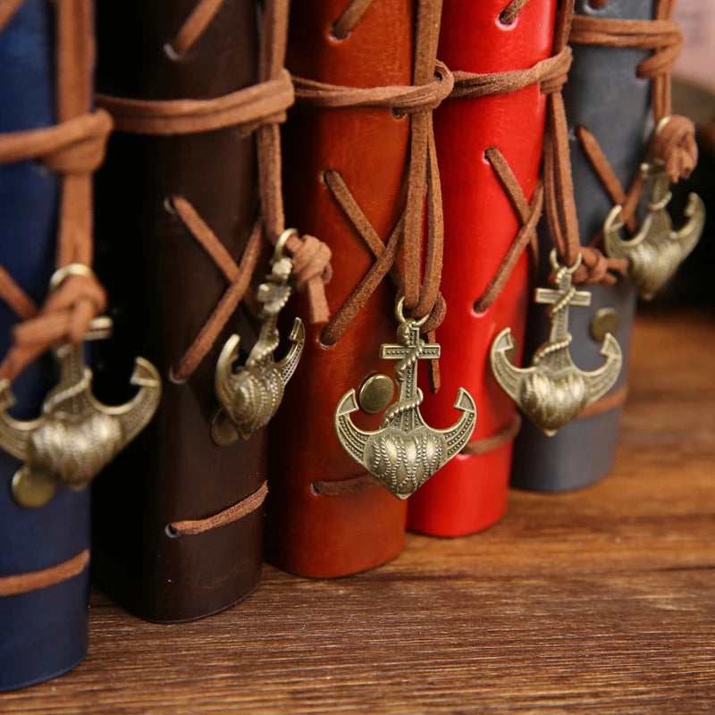 Set of leather-bound books with metal anchor pendants on a wooden surface