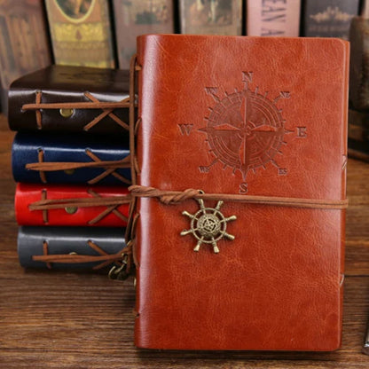 Brown leather notebook with compass design on a wooden surface