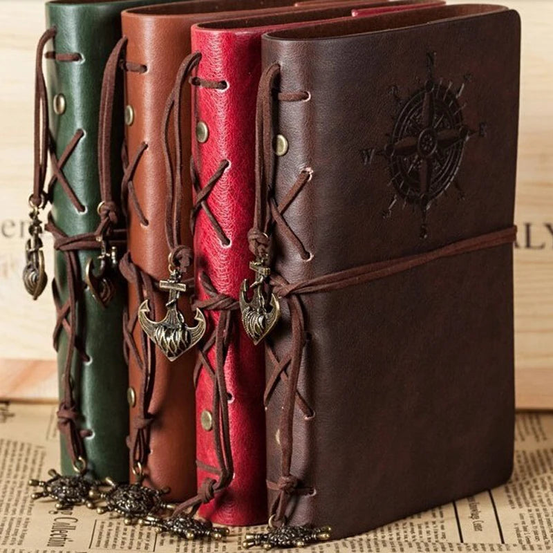 Four leather-bound books with decorative straps and embellishments on a newspaper background.
