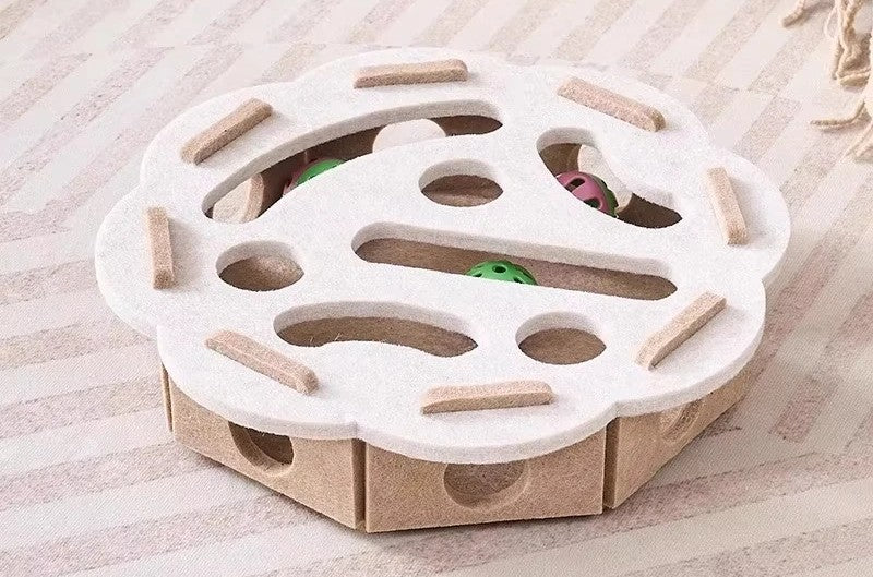 Cat toy with a white top and cardboard base on a wooden surface