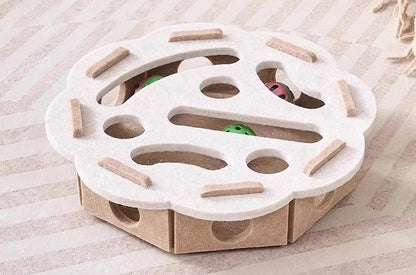 Cat toy with a white top and cardboard base on a wooden surface