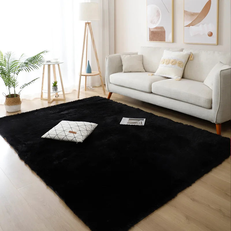 Black rug on a wooden floor in a living room with a white sofa and decor.